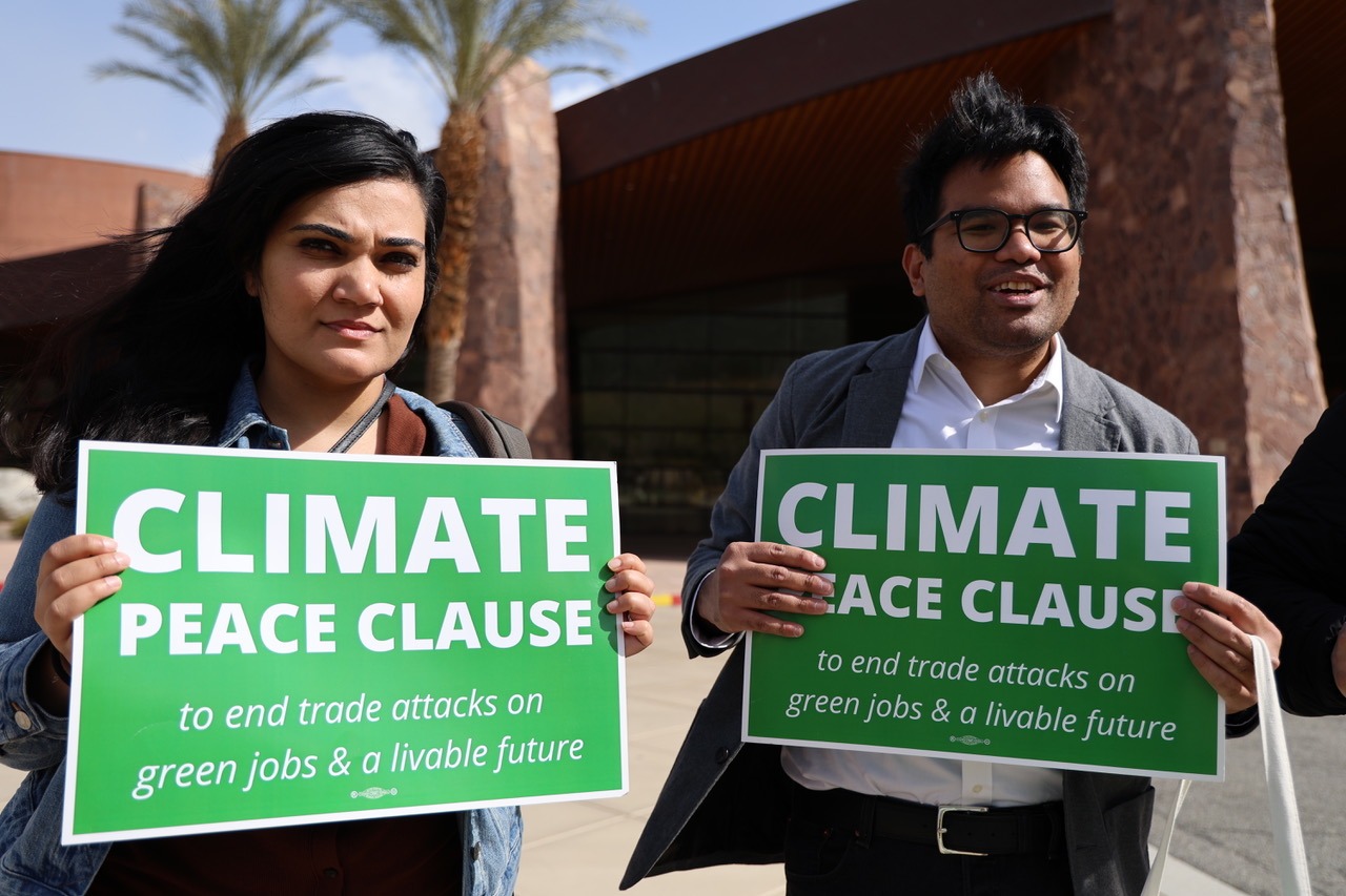 Two activists hold signs saying "Climate Peace Clause"